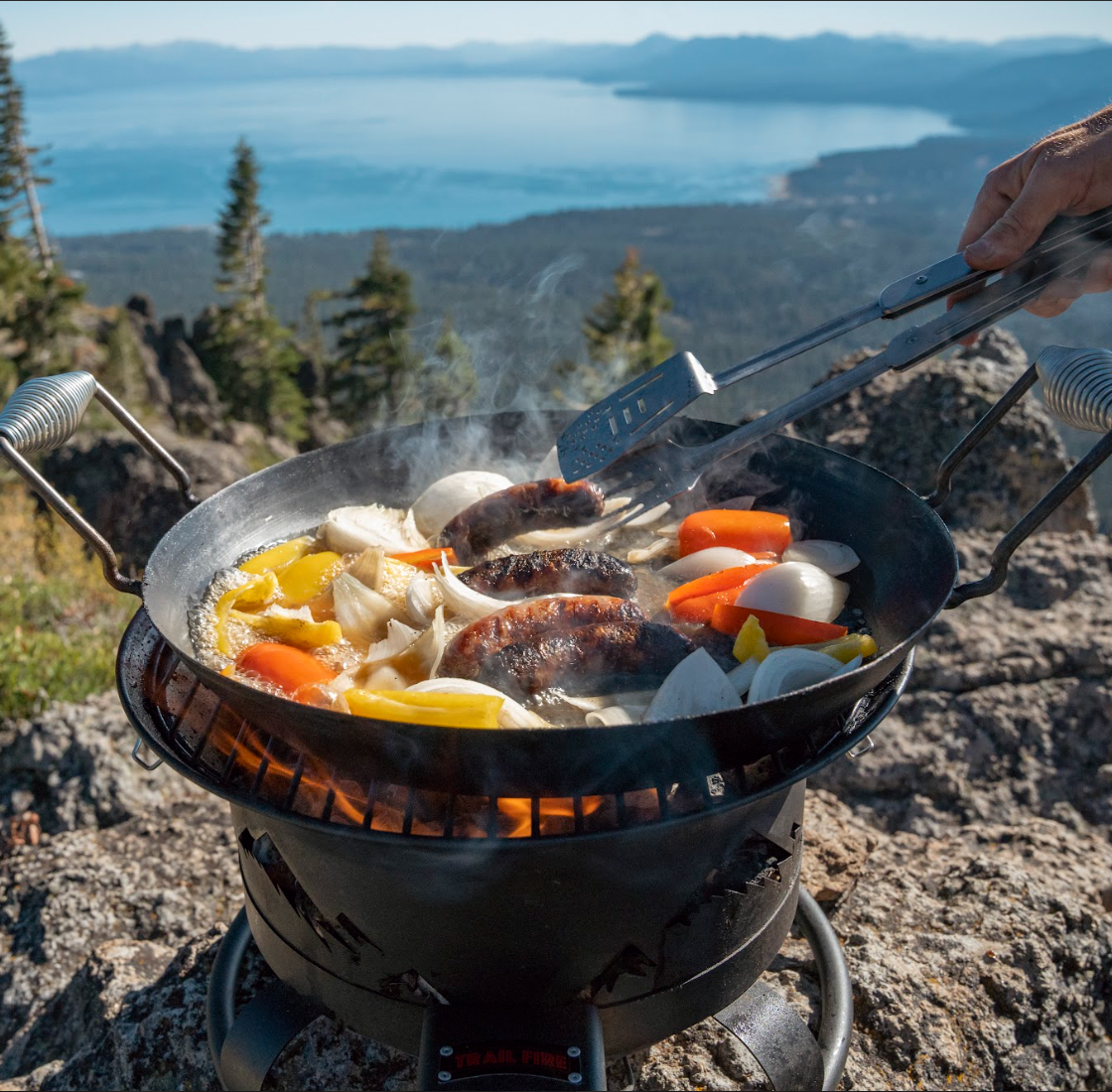 image that shows using the Trail Fire Grill in its Wok Mode cooking up vegetables and sausage with a view